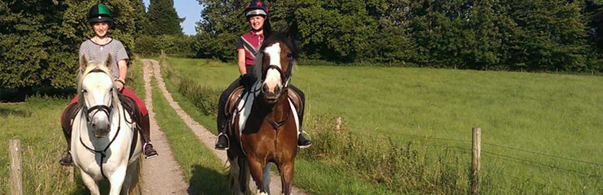 2 females riding horses on path